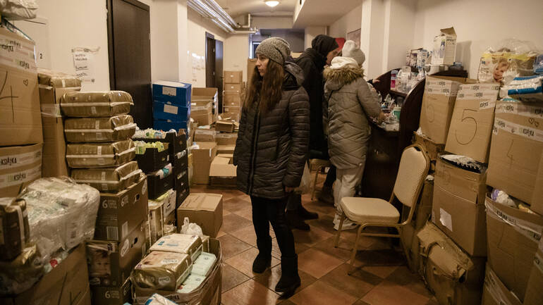 Frau steht inmitten von Hilfsgütern Frau steht inmitten von Hilfsgütern