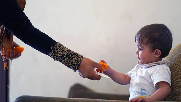 Dana gibt ihrem Sohn Akram (11 Monate) eine Aprikose. Dana gibt ihrem Sohn Akram (11 Monate) eine Aprikose.