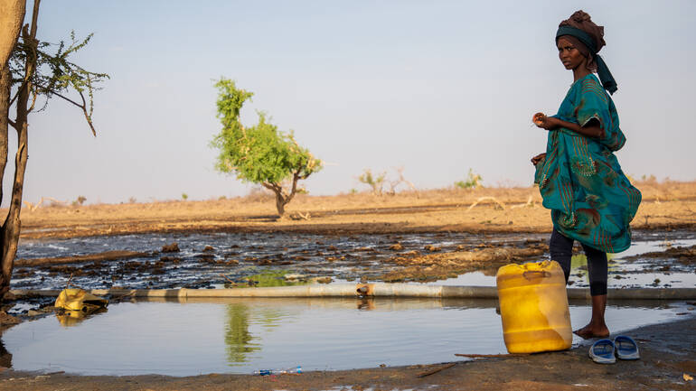 Eine Frau aus Kenia steht vor einem fast ausgetrockneten See. Eine Frau aus Kenia steht vor einem fast ausgetrockneten See.