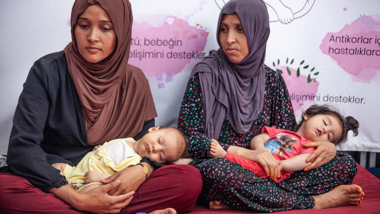 Zwei Mütter aus der Türkei mit ihren Kindern auf dem Schoß bei einem Stillkurs. Zwei Mütter aus der Türkei mit ihren Kindern auf dem Schoß bei einem Stillkurs.