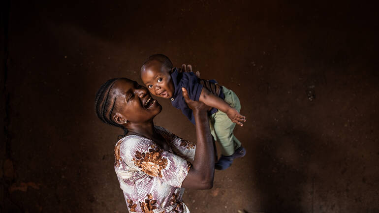 Mariam hält ihren Sohn hoch, beide lachen. Mariam hält ihren Sohn hoch, beide lachen.