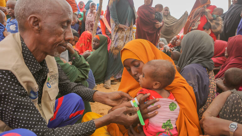 Im Geflüchtetencamp in Hudur, Somalia, untersucht unser mobiles Gesundheitspersonal die elf Monate alte Awliyo Ali mit einem MUAC-Band auf Mangelernärhung, während ihre Mutter Hawa Muse ihre Hand hält. 