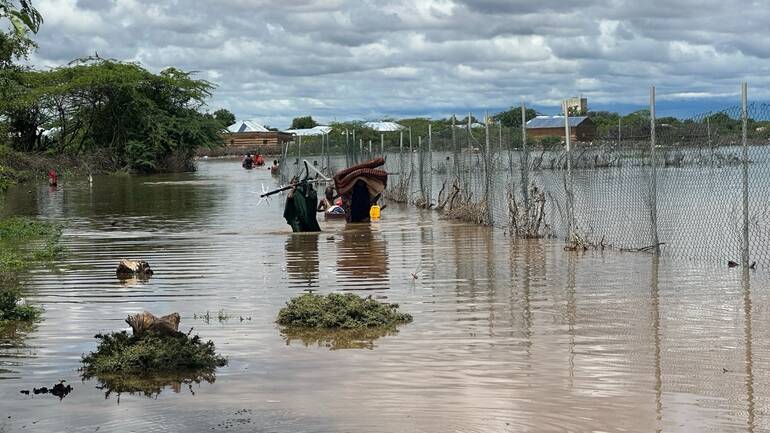 Eine Familie trägt ihre geretteten Habseligkeiten durch ein überflutetes Gebiet.