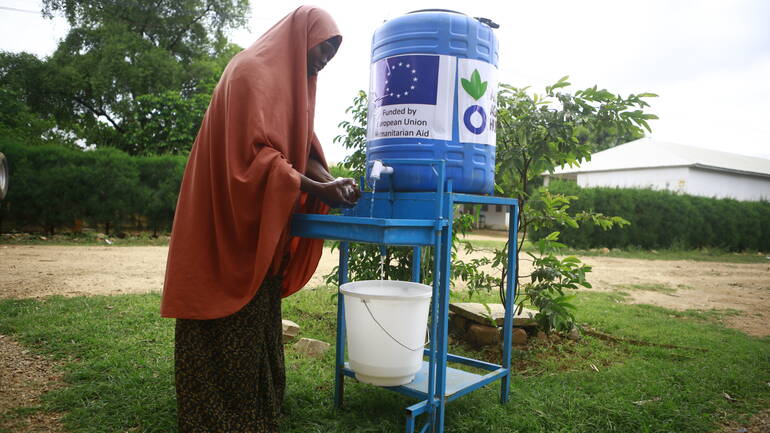 Eine Frau aus Somalia wäscht sich an einer Handwaschstation die Hände.