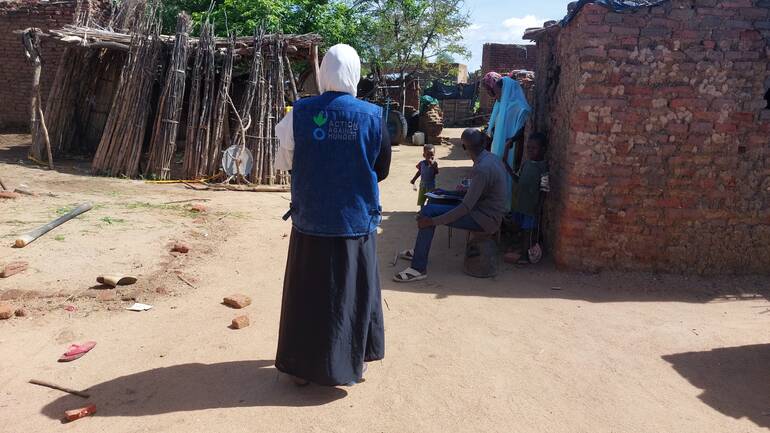 Eine Mitarbeiterin von Aktion gegen den Hunger läuft durch ein sudanesisches Dorf.
