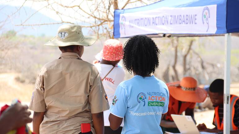 Unsere lokalen Projektmitarbeiter*innen vor einem Notfallzelt im Rahmen humanitärer Hilfe in Simbabwe