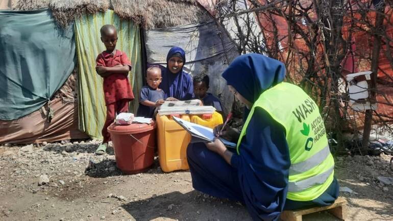 Owliya zuhause mit ihren Kindern, als sie ein Wasser- und Hygiene-Set von einer Mitarbeiterin von Aktion gegen den Hunger erhält.