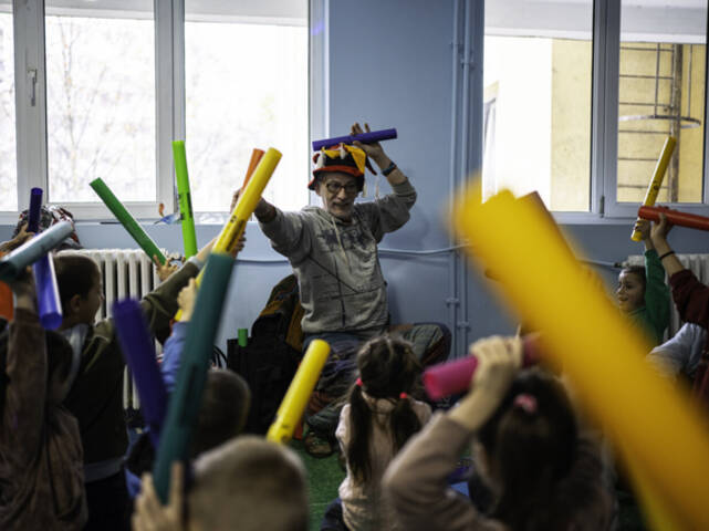 Ein Mitarbeiter macht zusammen mit einer Gruppe Kinder Musik.