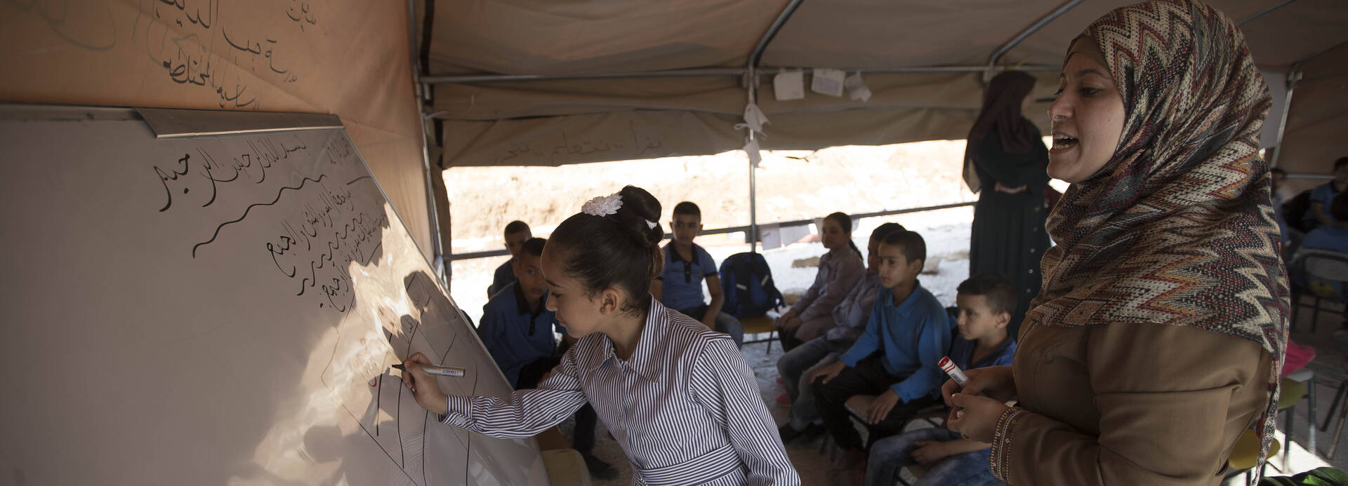 Mädchen schreibt im Klassenzimmer an der Tafel. Mädchen schreibt im Klassenzimmer an der Tafel.
