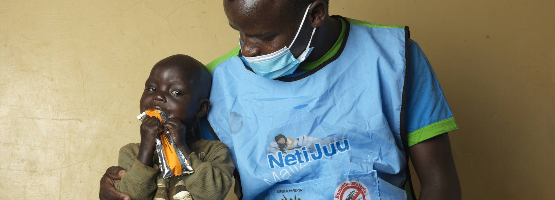 Erdnusspaste hat Chepengats Leben gerettet Chepengat sitzt mit einem Pfleger auf einer Liege, sie isst Erdnusspaste