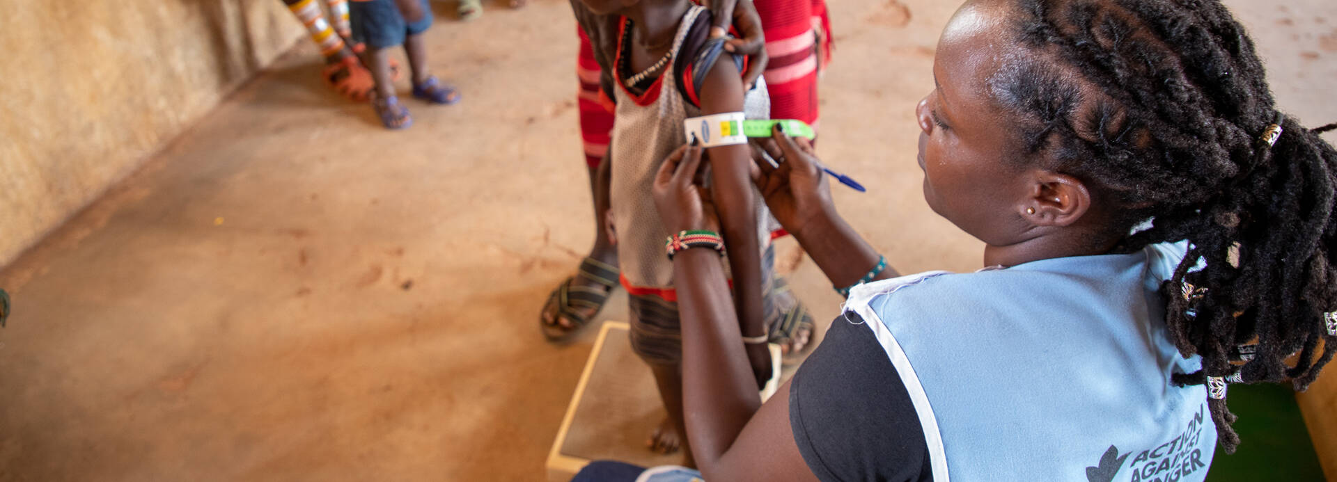 Mitarbeiterin von Aktion gegen den Hunger untersucht Kind auf Unterernährung Mitarbeiterin von Aktion gegen den Hunger untersucht Kind auf Unterernährung