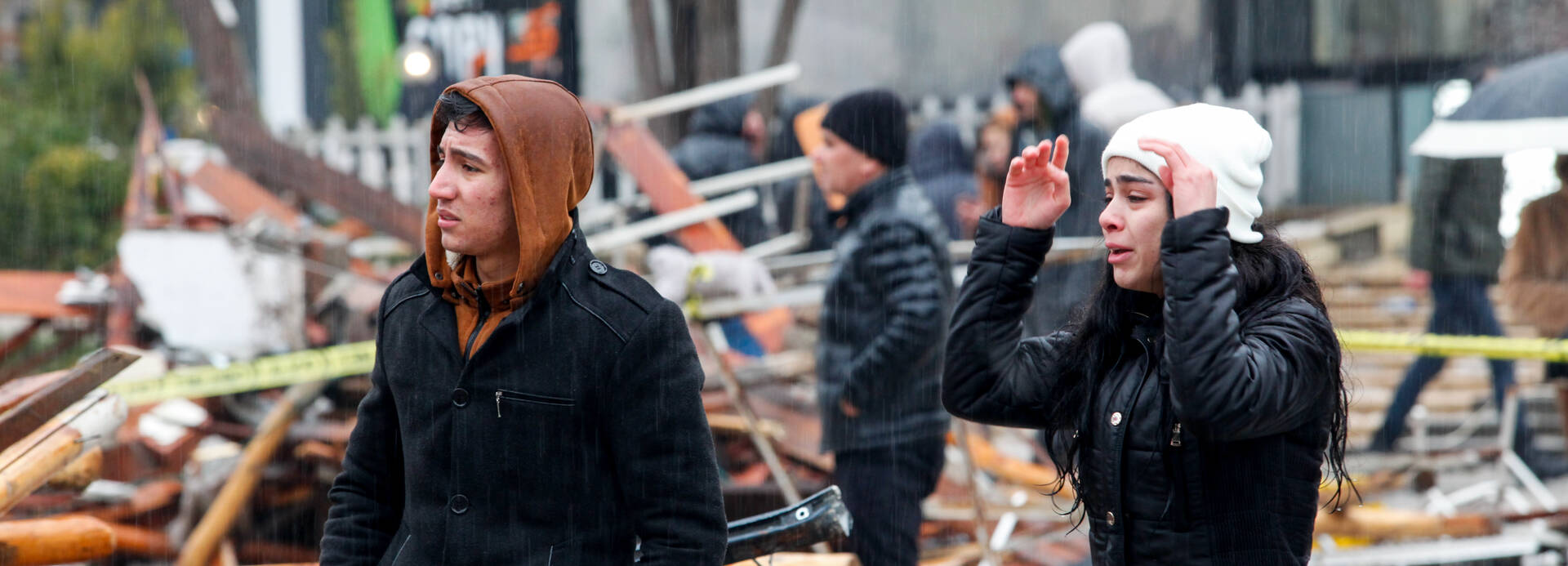 Ein junger Mann und eine junge Frau stehen verzweifelt vor den Trümmern in einer Straße nach dem schweren Erdbeben in der Türkei Ein junger Mann und eine junge Frau stehen verzweifelt vor den Trümmern in einer Straße nach dem schweren Erdbeben in der Türkei