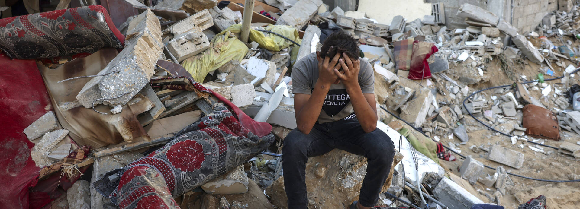 Ein palästinensischer Jugendlicher sitzt auf den Überresten seines zerstörten Hauses und vergräbt den Kopf in den Händen. Ein palästinensischer Jugendlicher sitzt auf den Überresten seines zerstörten Hauses und vergräbt den Kopf in den Händen.