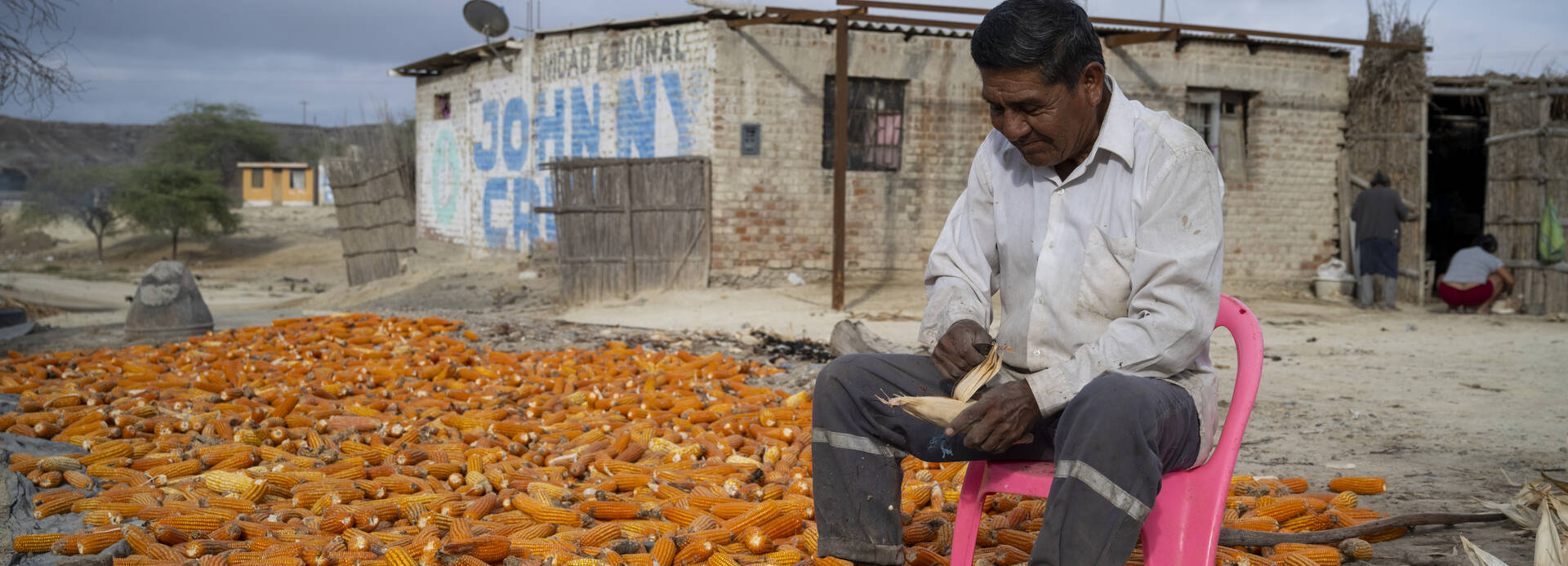 Ein Mann sitzt auf einem Stuhl in Piura, im Norden Perus, und schält Mais.
