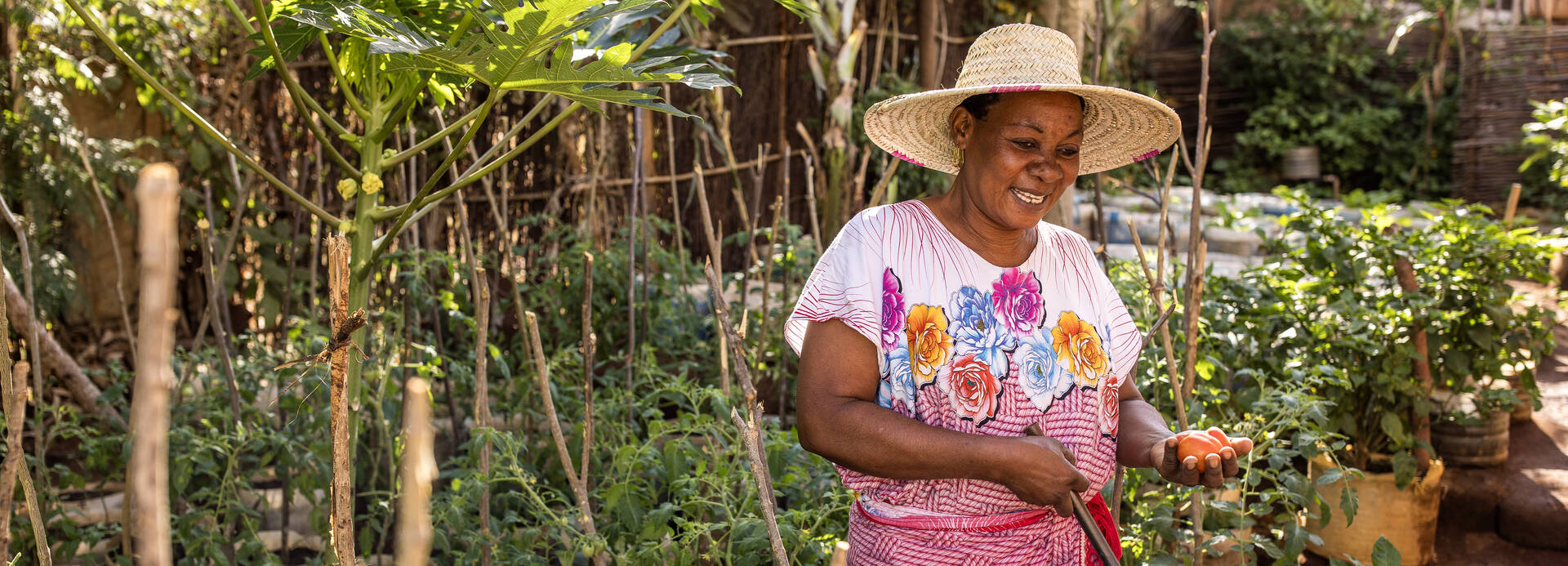 Salama Madinda steht lächelnd in ihrem Gemüsegarten