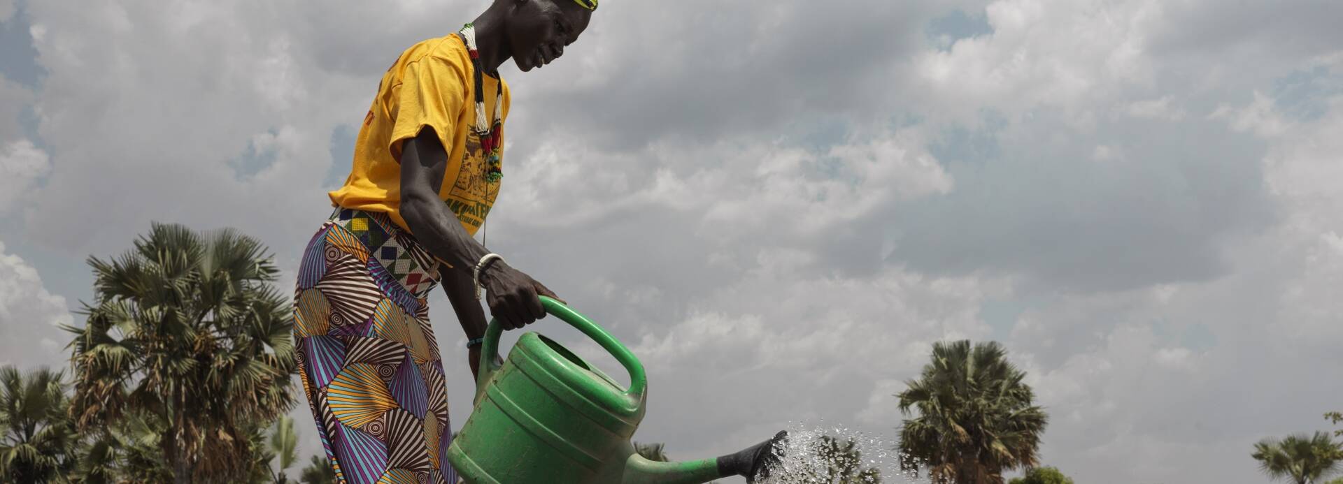 Eine Frau in Süsudan bewässert mit einer Gießkanne die angebauten Zwiebeln.