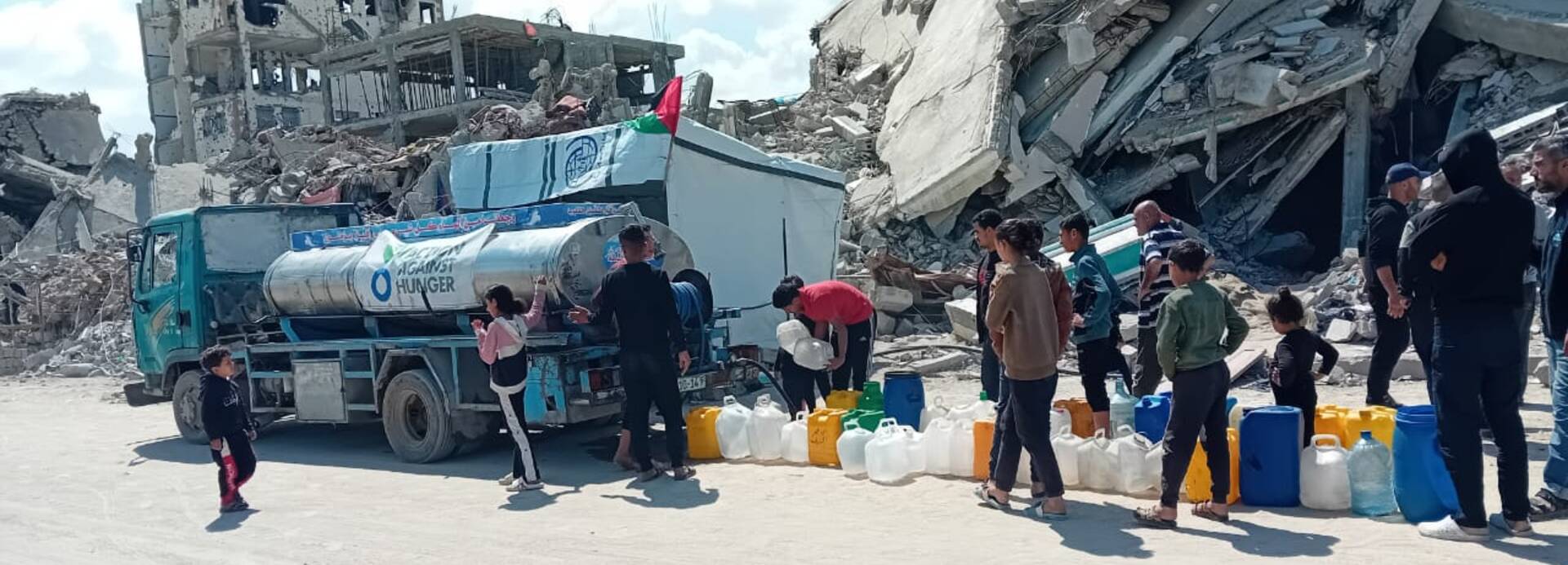 Wassertank in Gaza vor zerstörten Gebäuden im April 2025