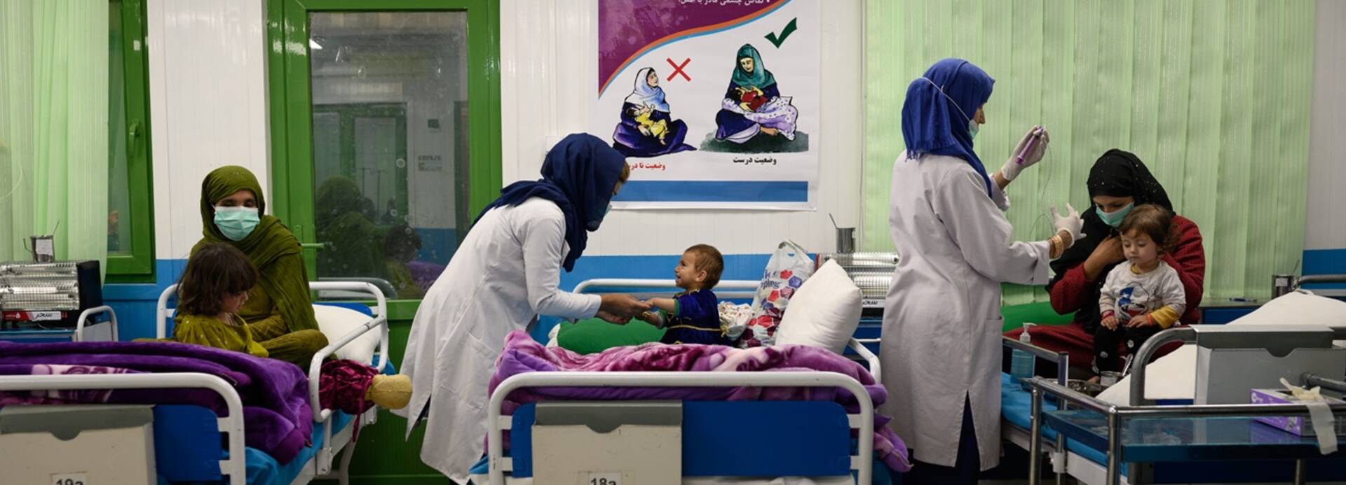Eine Krankenschwester kümmert sich um ein akut unterernährtes Kind, das an einer Lungenentzündung leidet und mit seiner Mutter in einer stationären Abteilung der therapeutischen Ernährungseinheit von Aktion gegen den Hunger in Kabul sitzt. 