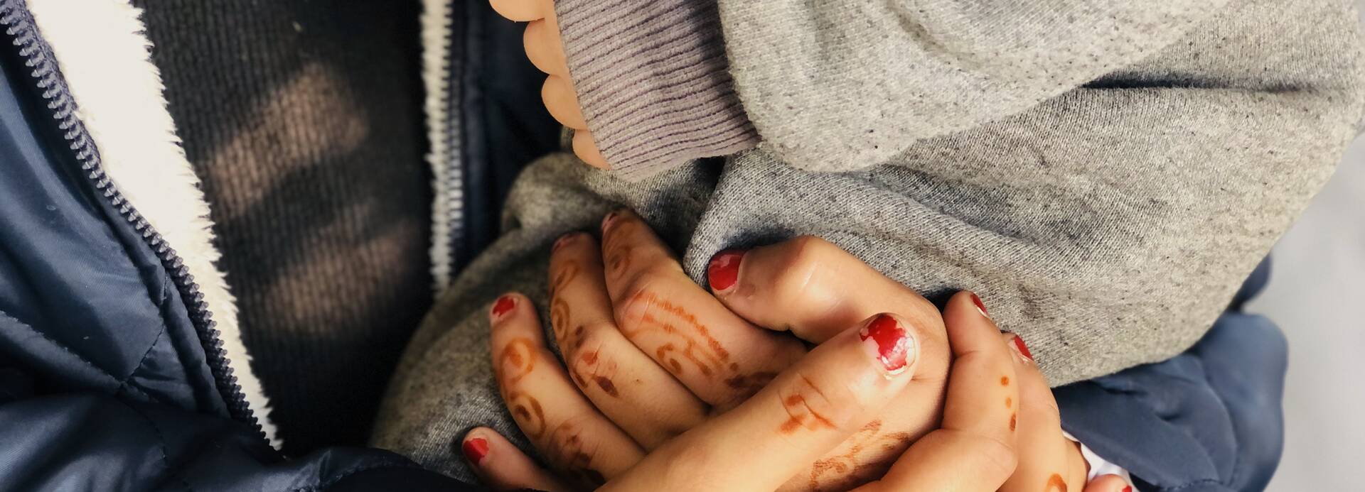 Eine Mutter hält schützend ihre Hände um ihr Kind.