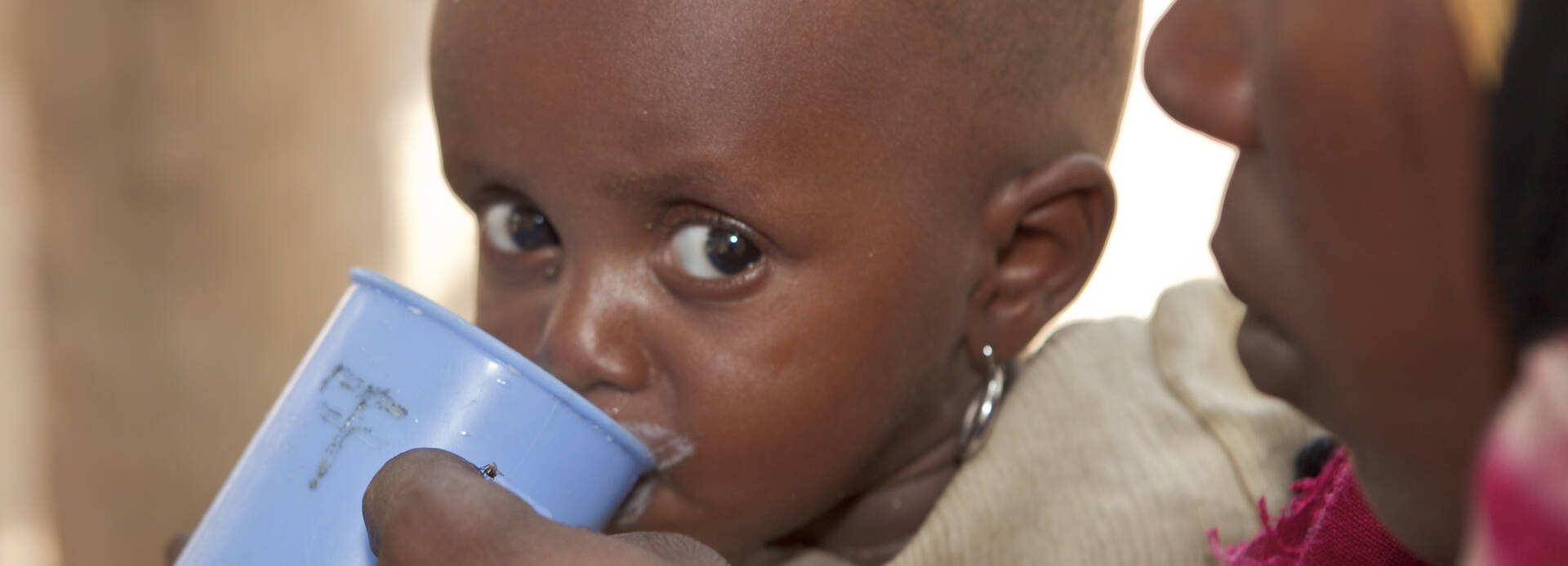 kind-wird-mit-tasse-gefüttert