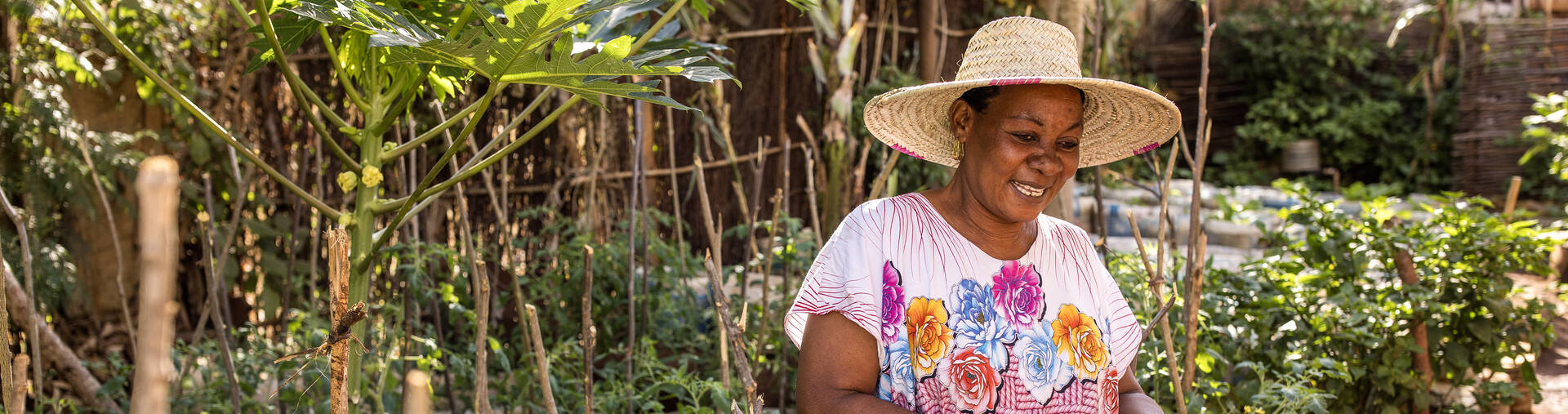 Salama Madinda steht lächelnd in ihrem Gemüsegarten