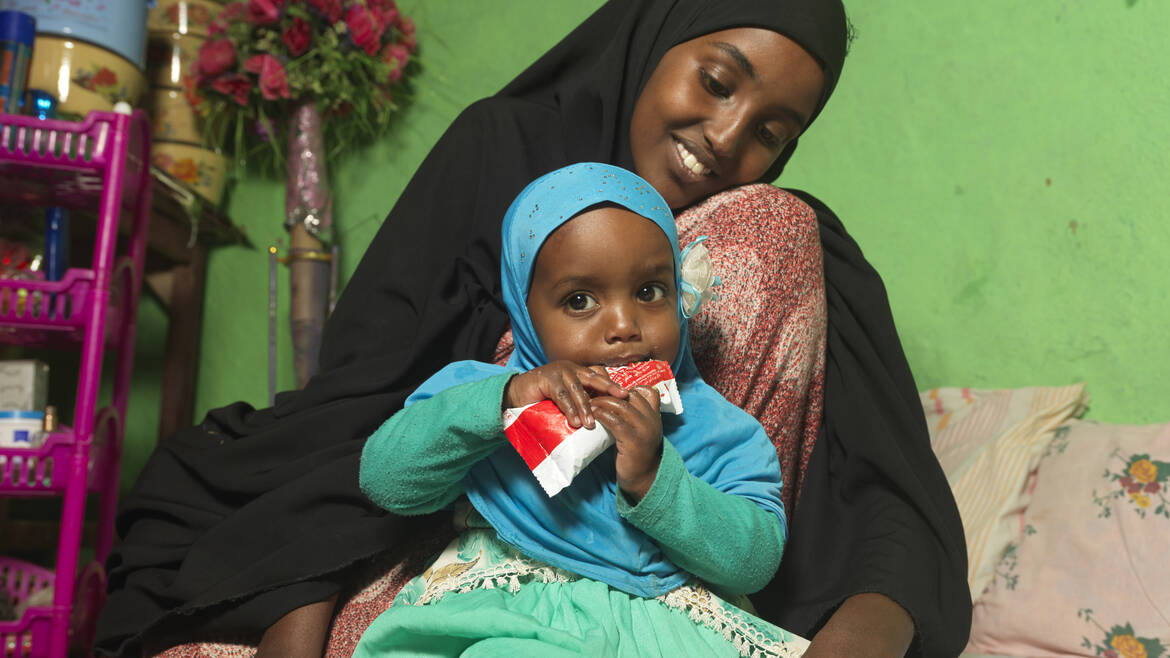 Kind isst Plumpy Nut im Arm ihrer Mutter