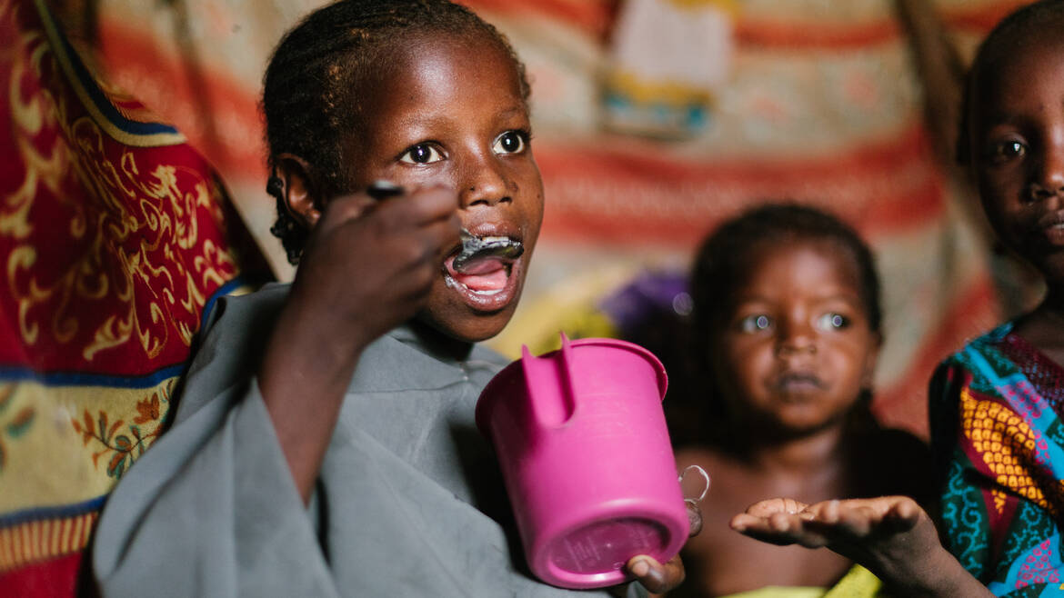 Kind isst aus einem Becher