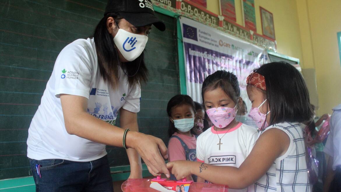 Mitarbeiter von Aktion gegen den Hunger übergibt Schulmaterial an Kinder