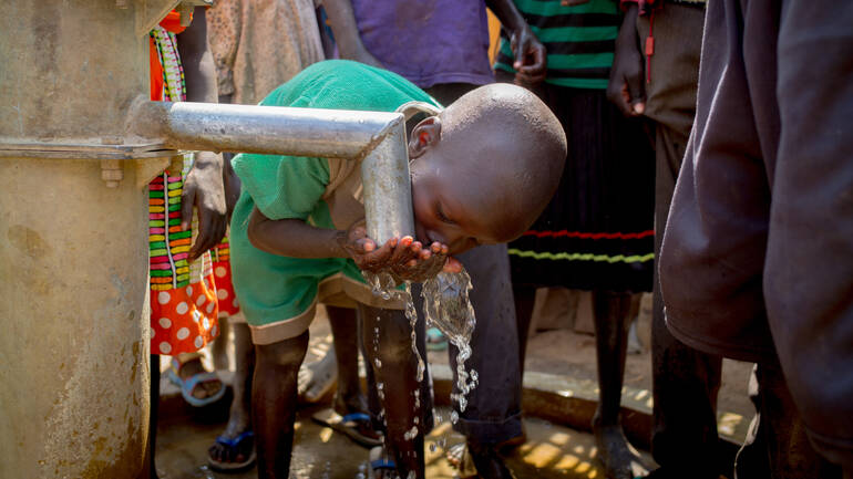 Kind aus dem Südsudan trinkt aus Brunnen Kind aus dem Südsudan trinkt aus Brunnen