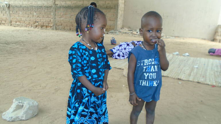 Zwei von Tenings Enkeln stehen auf dem trockenen Boden im Dorf.