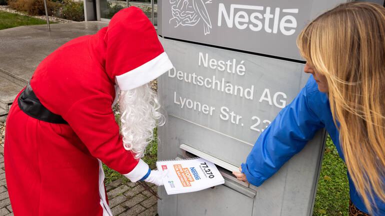 Der Nikolaus wirft mithilfe einer Campaignerin die Petitionsunterschriften in den Briefkasten der Nestlé-Zentrale in Frankfurt am Main. Der Nikolaus wirft mithilfe einer Campaignerin die Petitionsunterschriften in den Briefkasten der Nestlé-Zentrale in Frankfurt am Main.