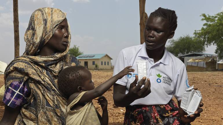 Nyibol Mathiang Deng, 27, und ihr Kind aus dem Sudan erhalten Energiekekse von Mary Anok Juac, die für Aktion gegen den Hunger arbeitet.