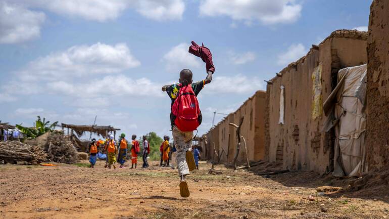 Rennendes Kind mit Rucksack in Mopti, Mali