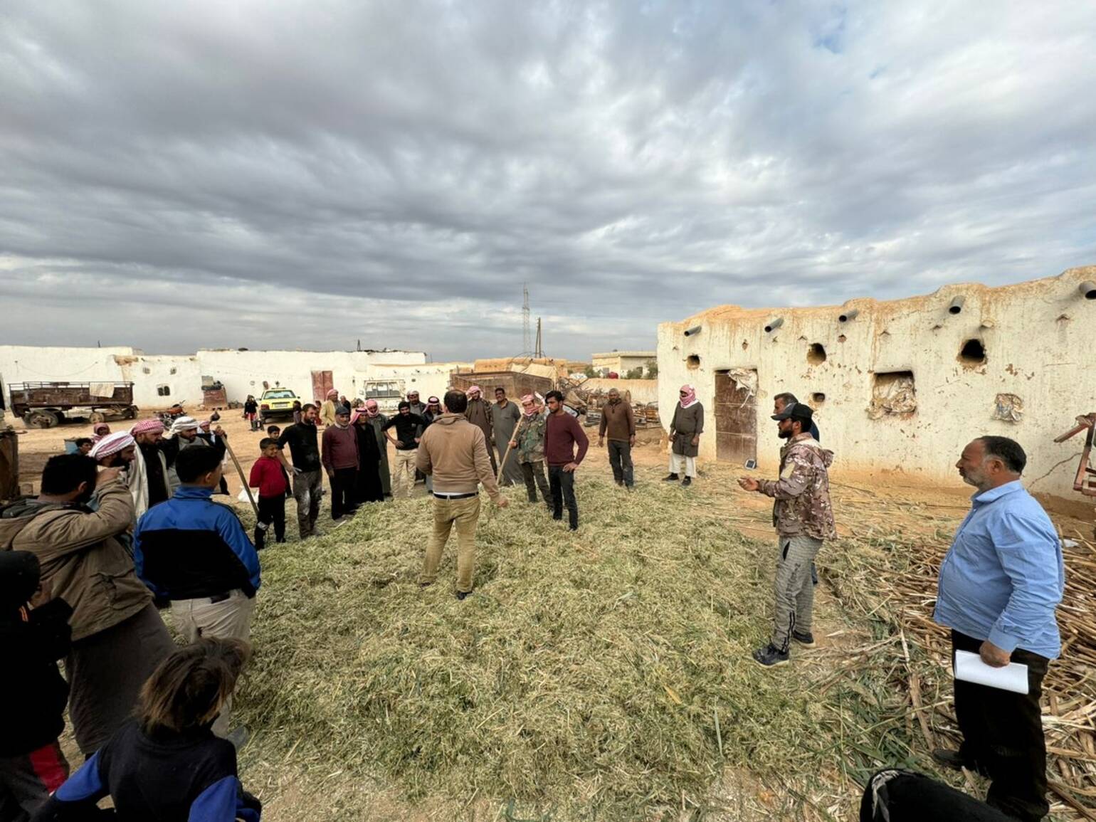 Landwirte*Landwirtinnen versammeln sich vor Ibrahims Haus zur Farm Field School.