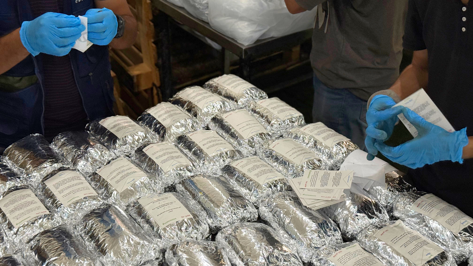 Mitarbeiter von Aktion gegen den Hunger kleben Solidaritätsbekundungen auf verpackte warme Mahlzeiten.