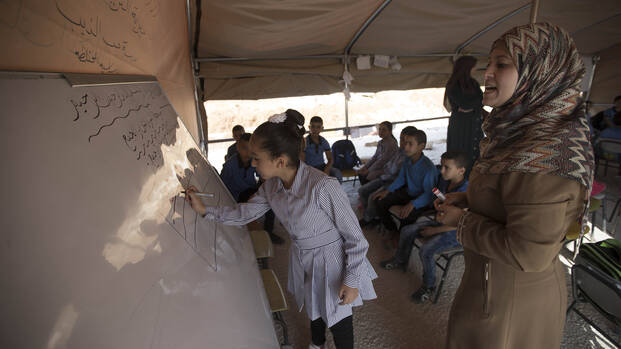Mädchen schreibt im Klassenzimmer an der Tafel. Mädchen schreibt im Klassenzimmer an der Tafel.