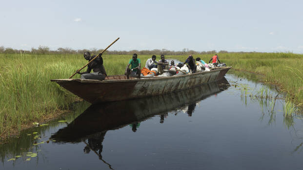 Menschen aus dem Südsudan befahren mit einem großen Boot eine der neuen Wasserstraßen in Paguir Menschen aus dem Südsudan befahren mit einem großen Boot eine der neuen Wasserstraßen in Paguir