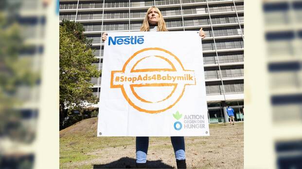 Unsere Kollegin steht vor der Nestlé-Zentrale in Frankfurt am Main und hält ein Banner mit einem orangefarbenen Stempel mit dem Hashtag #StopAds4Babymilk hoch. Unsere Kollegin steht vor der Nestlé-Zentrale in Frankfurt am Main und hält ein Banner mit einem orangefarbenen Stempel mit dem Hashtag #StopAds4Babymilk hoch.