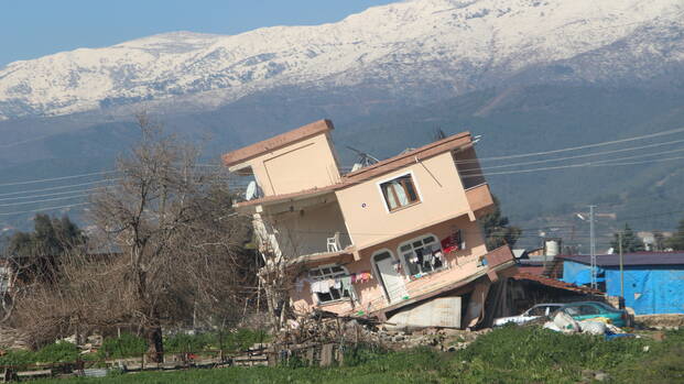 Ein Haus ist nach dem Erdbeben in der Region Hatay zur Seite gekippt, im Hintergrund Berge. Ein Haus ist nach dem Erdbeben in der Region Hatay zur Seite gekippt, im Hintergrund Berge.