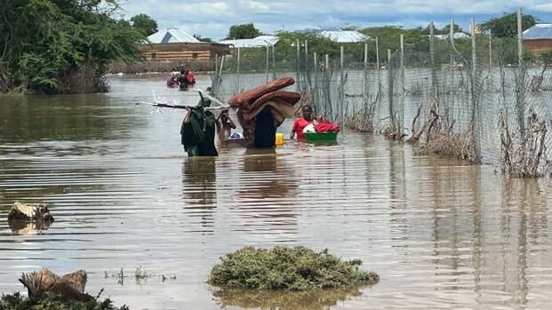 Eine Familie aus Somalia versucht, zumindest einen Teil ihrer Habseligkeiten vor den Überflutungen zu retten. Sie laufen durchs hüfthohe Wasser. Eine Familie aus Somalia versucht, zumindest einen Teil ihrer Habseligkeiten vor den Überflutungen zu retten. Sie laufen durchs hüfthohe Wasser.