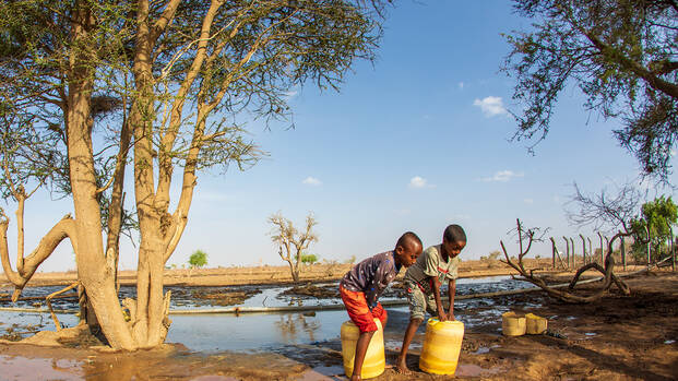 Zwei Kinder aus Kenia beim Wasser holen mit gelben Kanistern Zwei Kinder aus Kenia beim Wasser holen mit gelben Kanistern