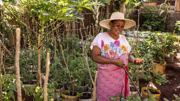 Salama Madinda steht lächelnd in ihrem Gemüsegarten